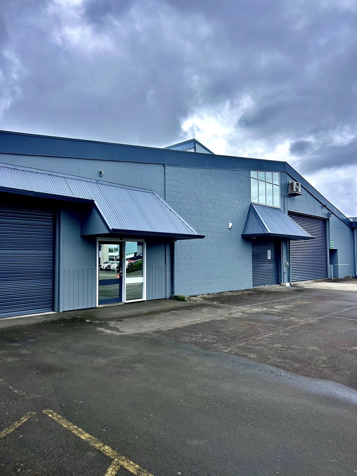 Commercial building after repainting, with coordinated blue-grey walls, awnings and roller doors