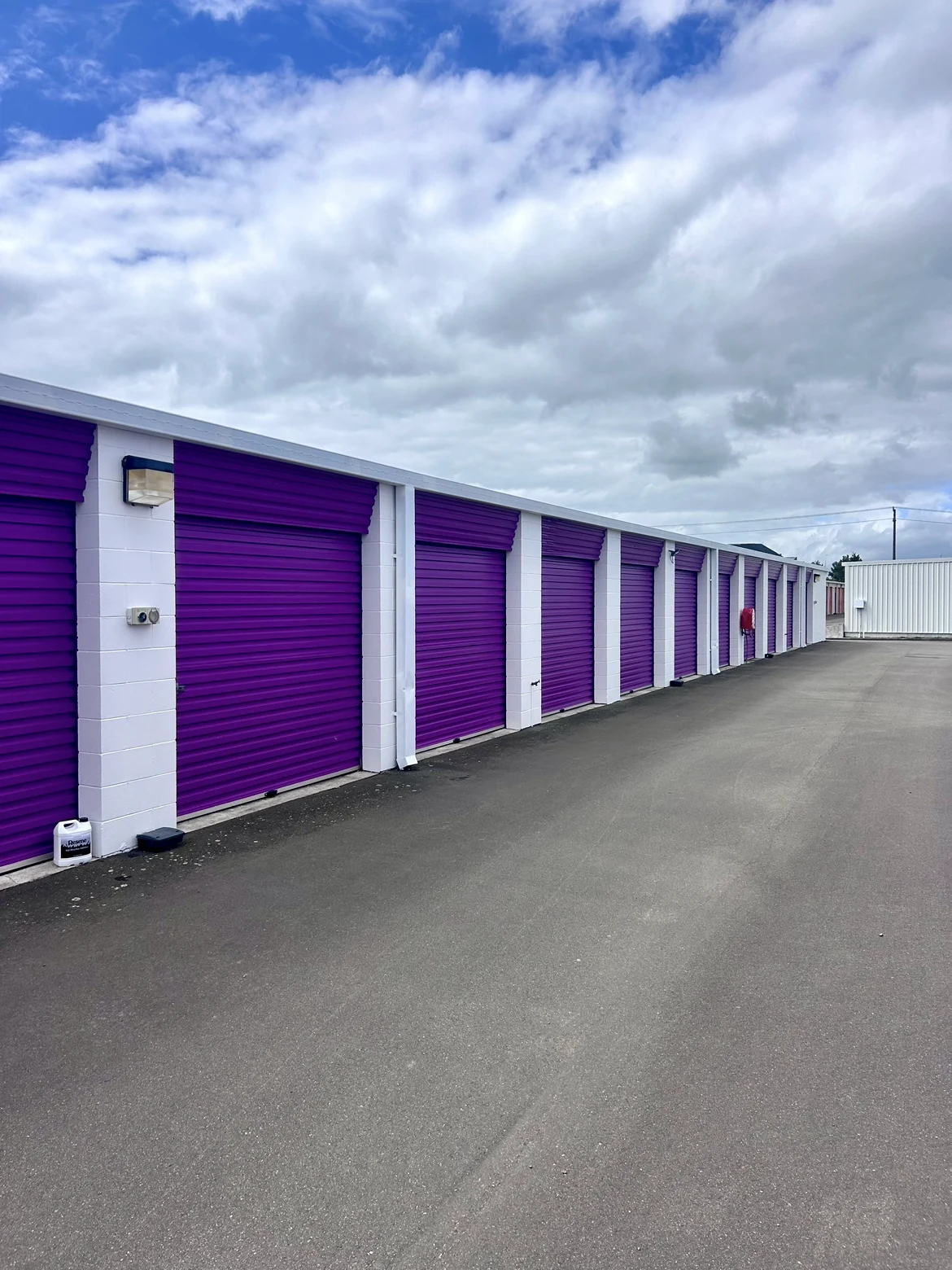 Storage units after repainting, with purple roller doors and white dividing walls